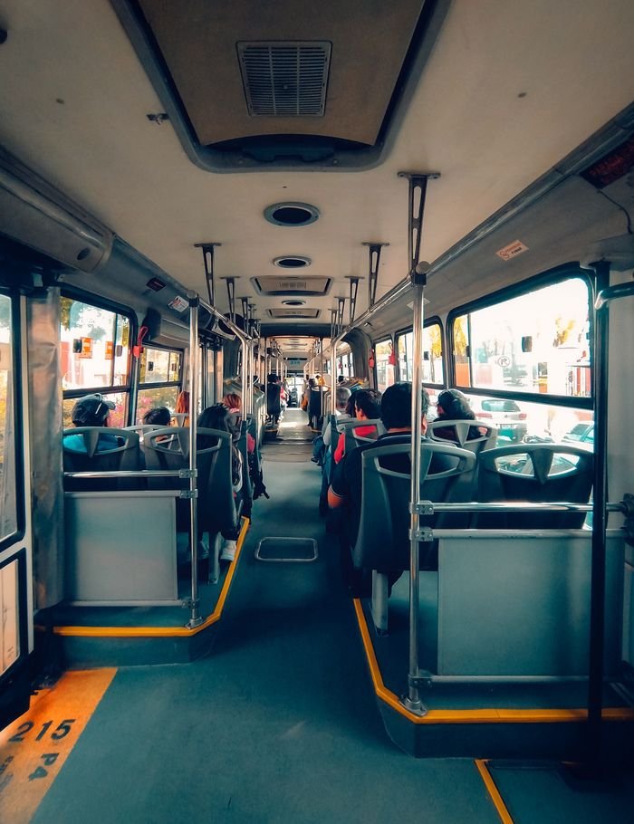 View inside an urban bus showing passengers seated during the day.